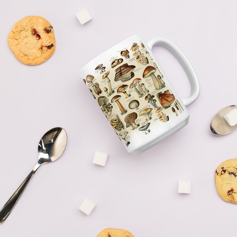 Peut inclure: Une tasse en c&eacute;ramique blanche avec une illustration vintage de diff&eacute;rents types de champignons. La tasse a une anse sur le c&ocirc;t&eacute; droit.