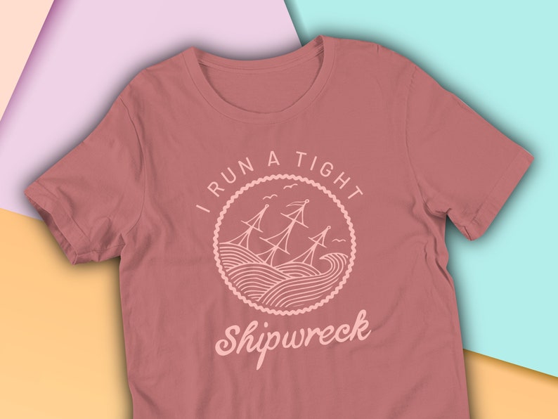 May include: A maroon t-shirt with a white graphic design of a ship in a circle with the text "I run a tight shipwreck".