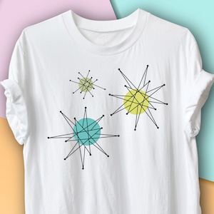 Peut inclure: T-shirt blanc avec un motif graphique de trois étoiles noires avec des cercles jaunes et turquoise au centre.