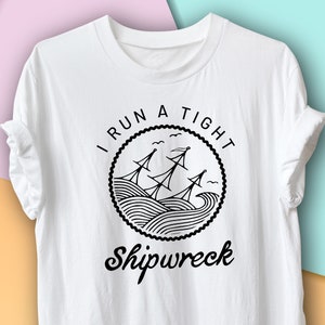 May include: White t-shirt with a black graphic design that says "I run a tight shipwreck". The graphic features a ship with sails and waves.