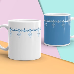 May include: Two white ceramic mugs with blue snowflake designs. One mug is filled with a blue liquid, while the other is empty.