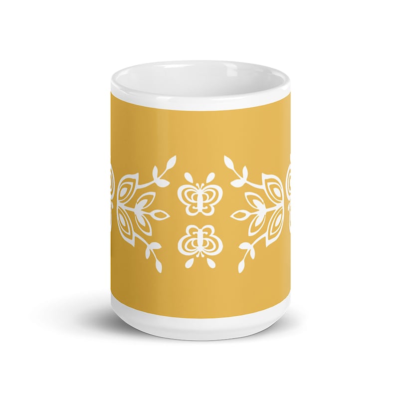 Pu&ograve; includere: Una tazza in ceramica gialla con un design floreale e farfalla bianco. La tazza &egrave; di dimensioni standard e ha un interno bianco.