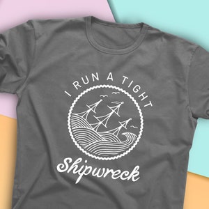 May include: Gray t-shirt with a white graphic design of a ship in a circle with the text "I run a tight shipwreck".