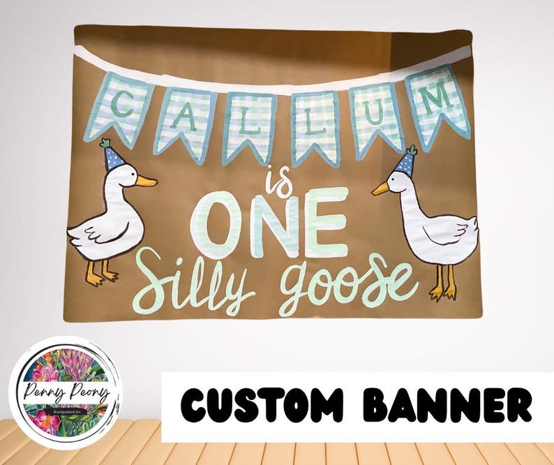 May include: A brown banner with the text "CALLUM is ONE Silly goose" in white and light green. Two cartoon geese wearing party hats flank the text. The banner has a light blue and white checkered banner across the top.