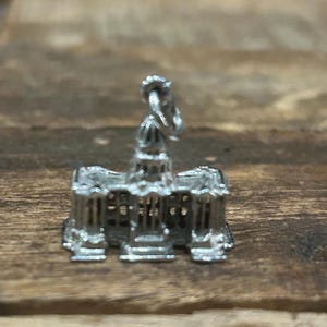 May include: Silver charm in the shape of a building with a domed roof. The charm is detailed with columns and windows.