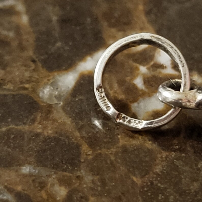 Op de afbeelding: Close-up van een zilveren ring met het woord "Sterling" gestempeld aan de binnenkant.