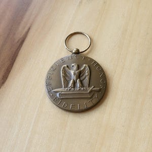 May include: A bronze medal with an eagle and sword design. The medal is inscribed with the words "Efficiency Honor Fidelity".