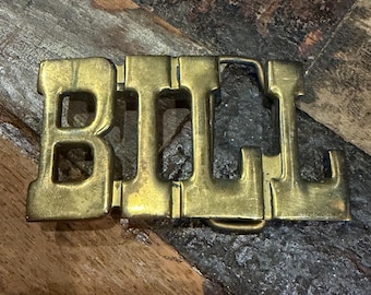 Vintage 1970s solid brass belt buckle featuring chunky, interlocking block letters that spell out the name "BILL”
