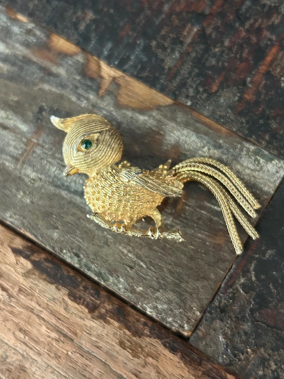 Vintage gold tone bird brooch with green jeweled eye and mesh chain flume tail