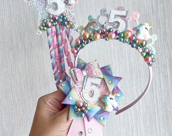May include: A unicorn themed birthday headband set with a pink headband, a star wand with a rainbow and a unicorn, and a rainbow ribbon with a unicorn and the number 5.