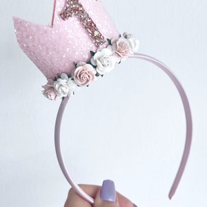 May include: Pink felt crown headband with a glittery number one and pink and white flowers.