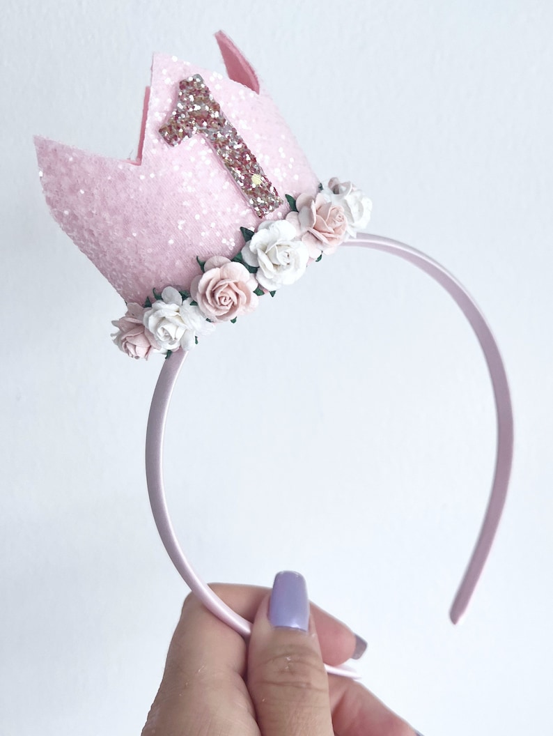 May include: Pink felt crown headband with a glittery number one and pink and white flowers.