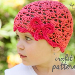 May include: A close-up of a child wearing a pink crocheted hat with a flower design. The hat has a scalloped edge and a bow on top. The child is looking to the side. The text "crochet pattern" is visible in the image.