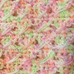 May include: Close-up of a crocheted fabric with a mix of pink, green and white yarn.