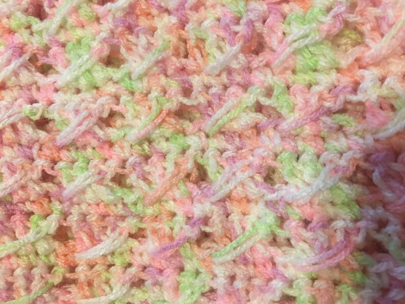 May include: Close-up of a crocheted fabric with a mix of pink, green and white yarn.