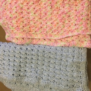 May include: Two crocheted baby blankets, one in pink and green and one in light blue.