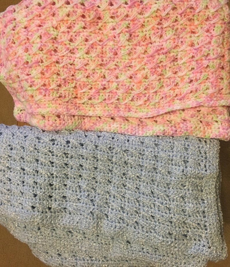 May include: Two crocheted baby blankets, one in pink and green and one in light blue.