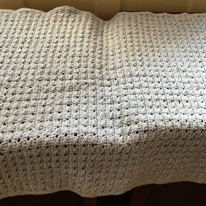 May include: A light blue crocheted baby blanket with a textured diamond pattern.