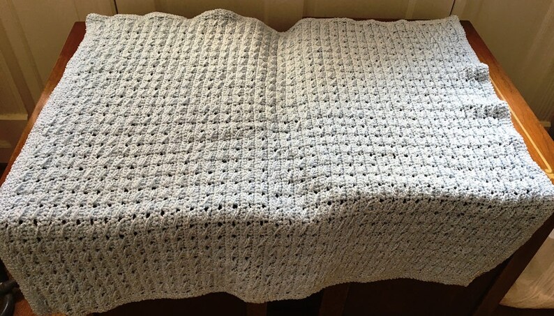 May include: A light blue crocheted baby blanket with a textured diamond pattern.