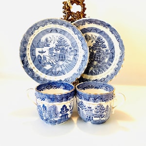May include: Two blue and white teacups with gold trim and a matching saucer set. The teacups and saucers feature a traditional willow pattern.