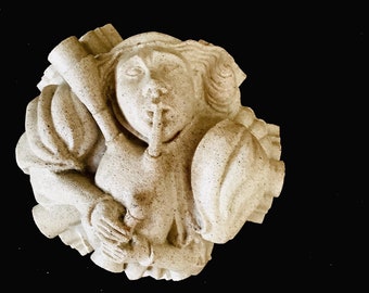 May include: A white stone sculpture of a person with their finger to their lips, as if to say "shh". The sculpture is carved in a detailed style, with intricate folds in the clothing.