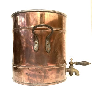 May include: A vintage copper water dispenser with a wooden handle and a spout. The dispenser has a rounded body with a single handle and a silver-colored top.