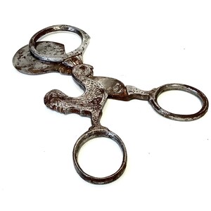 May include: Antique silver-toned metal cigar cutter shaped like a rooster. The cutter has two circular handles and a blade that is hidden when closed.