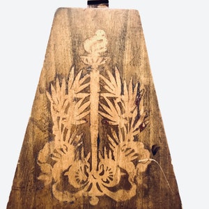 Könnte beinhalten: Ein Holzmusikinstrument mit einem dreieckigen Korpus und einem langen Hals. Der Korpus ist mit einem geschnitzten Design einer Pflanze mit Blättern und einem Vogel verziert.
