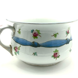 Puede incluir: Bote de cerámica blanca con un diseño de cinta azul y detalles florales de rosas rosas.