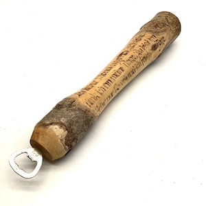 Puede incluir: Un abridor de botellas de madera con un abridor de metal en el extremo. La madera es natural con corteza todavía en ella. La madera está grabada con el texto "Drink in the moment, embrace the good times, cherish the memories, and never forget the people who make you smile."