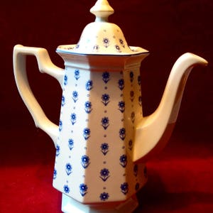 May include: White ceramic coffee pot with a blue and white floral pattern. The pot has a octagonal body and a lid with a knob.
