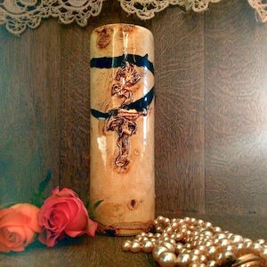 Könnte beinhalten: Eine Keramikvase mit brauner und schwarzer Glasur. Die Vase hat eine strukturierte Oberfläche und ein Design eines stilisierten Baumes mit Ästen. Die Vase steht auf einer Holzoberfläche mit einer Perlenkette davor.