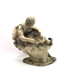 Puede incluir: Una escultura de cerámica de una persona sentada sobre una cabeza grande, ambas de color beige con detalles verdes.