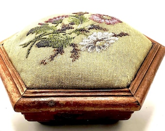 May include: A hexagonal wooden footstool with a floral embroidered top. The embroidery features a green, white, and pink floral design.