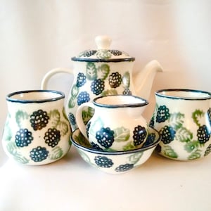 May include: A set of five ceramic teacups and a teapot with a black and green blackberry pattern. The set includes a creamer, a sugar bowl, and two teacups.