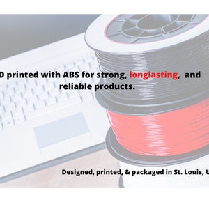Puede incluir: Tres carretes de filamento para impresi&oacute;n 3D. Los carretes son negros, rojos y blancos. El texto en la imagen dice "Impreso en 3D con ABS para productos fuertes, duraderos y confiables. Dise&ntilde;ado, impreso y empaquetado en St. Louis, USA."