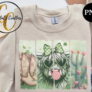 May include: A beige sweatshirt with a graphic print of a Highland cow wearing heart-shaped sunglasses, a bow, and a bubble, along with a pair of cowboy boots and a cactus with hearts.
