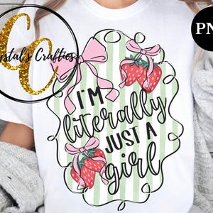 May include: A white t-shirt with a green and white striped design featuring pink bows and strawberries. The text "I'm literally just a girl" is written in a black script font.
