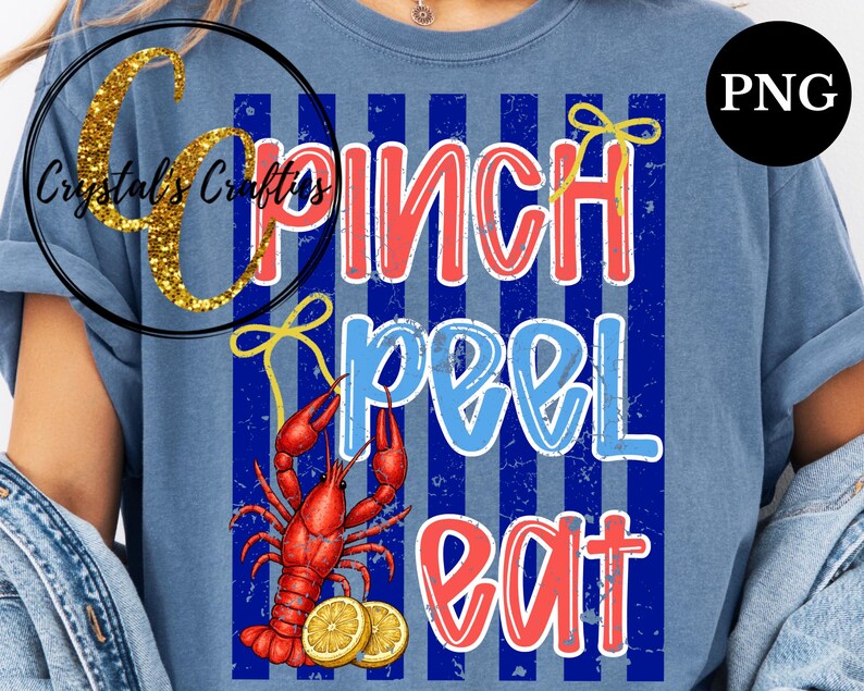 May include: Blue t-shirt with a graphic design featuring the words "Pinch Peel Eat" in red and blue, with a red crawfish and lemon slices. The design is set against a blue and white striped background.