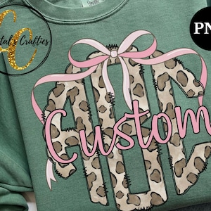 May include: A pink and brown monogram with a leopard print design and a pink bow. The monogram says "Custom".