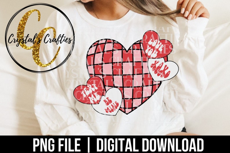 May include: A white t-shirt with a red and pink checkered heart design. The heart is surrounded by four smaller hearts with the text "Love You", "XOXO", "Text Me", and "Be Mine".
