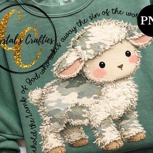 Puede incluir: Una sudadera verde salvia con un dise&ntilde;o de cordero de dibujos animados. El cordero tiene un patr&oacute;n de camuflaje y detalles en rosa. El texto dice "he aqu&iacute; el Cordero de Dios que quita el pecado del mundo". La marca "Crystal's Crafties" tambi&eacute;n es visible.