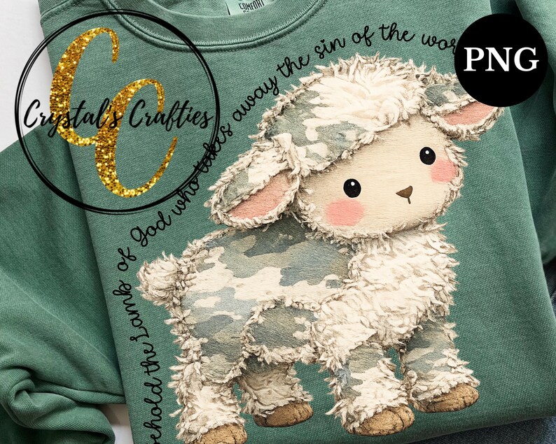 Puede incluir: Una sudadera verde salvia con un dise&ntilde;o de cordero de dibujos animados. El cordero tiene un patr&oacute;n de camuflaje y detalles en rosa. El texto dice "he aqu&iacute; el Cordero de Dios que quita el pecado del mundo". La marca "Crystal's Crafties" tambi&eacute;n es visible.