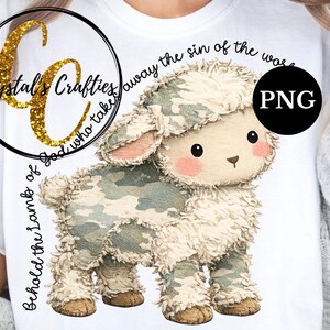 Puede incluir: Camiseta blanca con un cordero de dibujos animados con un patr&oacute;n de camuflaje. El cordero tiene mejillas y orejas rosas. El texto alrededor del cordero dice: "He aqu&iacute; el Cordero de Dios que quita el pecado del mundo". Un logotipo dorado con purpurina est&aacute; en la parte superior izquierda.