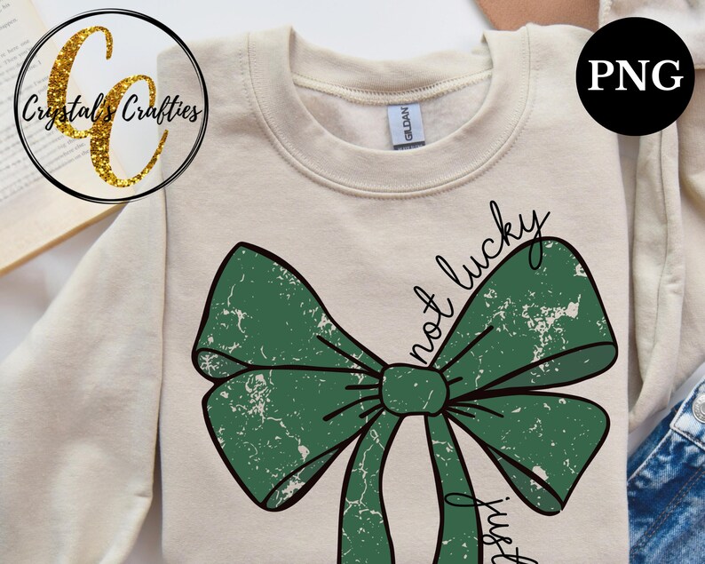 May include: A beige sweatshirt with a green bow and the text "not lucky just gifted" in black.