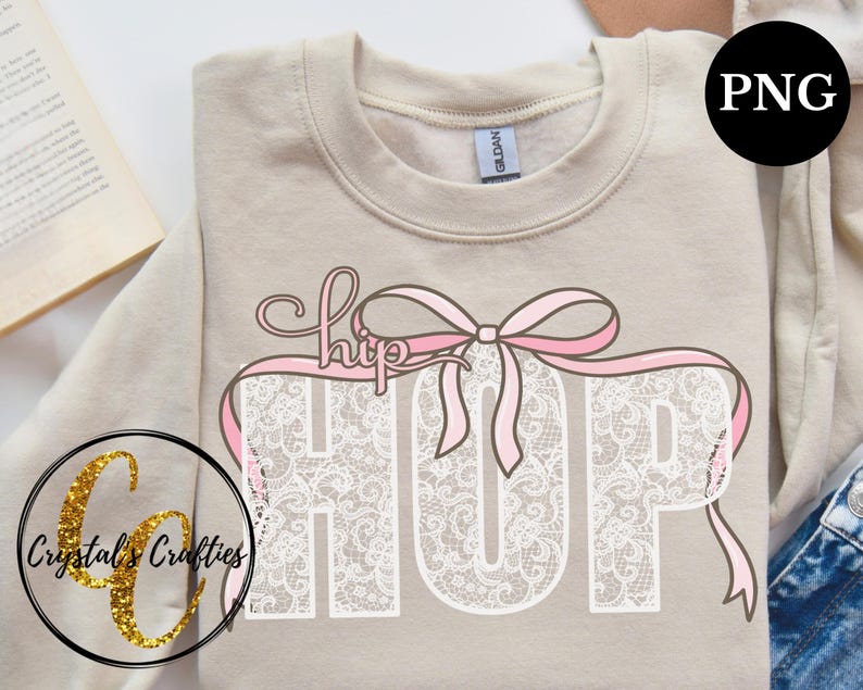 May include: A beige sweatshirt with a white lace design that spells out "HIP HOP" with a pink ribbon bow on top. The text "hip" is written in cursive.
