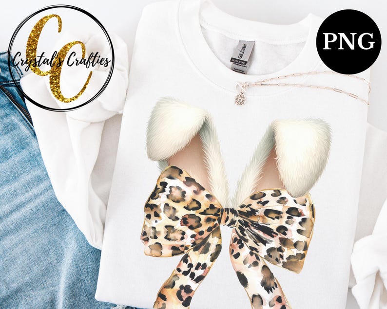 May include: A white t-shirt with a large leopard print bow with white fur accents. The bow is centered on the shirt.
