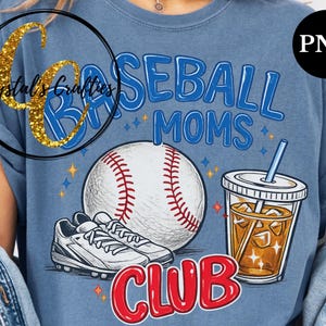 May include: Blue t-shirt with a baseball theme. The shirt features the words "Baseball Moms Club" in blue and red, a baseball, a pair of cleats, and a drink with a straw. The shirt has a vintage, distressed look.