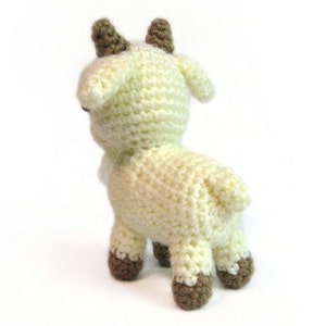 May include: A crocheted goat toy with brown horns and hooves. The goat is white and has a fluffy texture.
