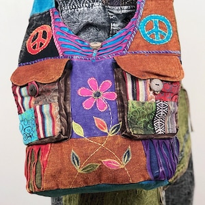 May include: A patchwork shoulder bag with a bohemian design. The bag features various fabrics in shades of brown, blue, purple, and green. It has two pockets, a flower applique, and peace symbols. The bag is adorned with embroidered details and wooden buttons.